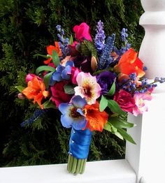 a bouquet of colorful flowers sitting on top of a white fence