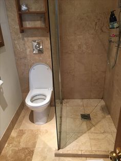 a bathroom with a toilet, shower and tiled floored walls is shown in this image