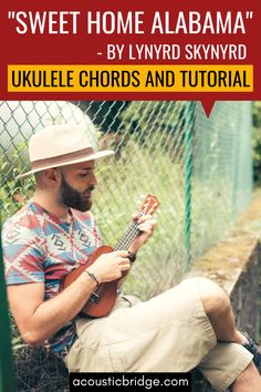 a man sitting on a fence playing an ukulele