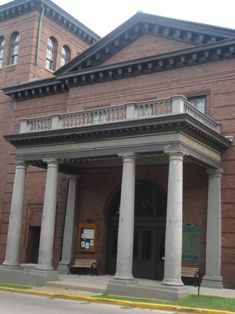 an old brick building with columns on the front and second story above it's entrance