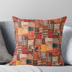 an orange and red patchwork pillow on a couch