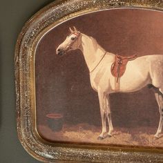 a painting of a white horse with a saddle on it's back, in a gold frame