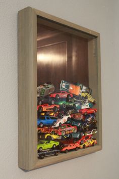 a group of toy cars sitting in a wooden box on the wall next to a mirror