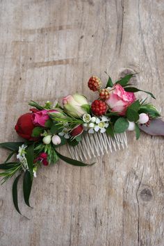 a hair comb decorated with flowers and leaves on top of a wooden table next to a piece of wood