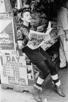 a woman sitting on top of a newspaper stand