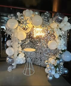 a birthday party backdrop with balloons and silver balls on the wall, snowflakes in the background