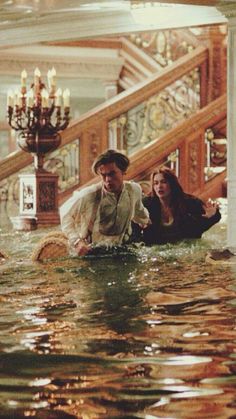 a man and woman are standing in the water at the bottom of an escalator