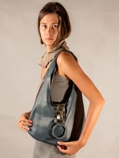 Hobo Bag, the perfect accessory to add a touch of magic and elegance to your everyday style. Made with high-quality genuine leather, this bag is designed to be both soft and sturdy, making it the perfect companion for any adventure. The Mother of Pearl decorated flap adds a touch of sophistication and beauty to the bag, while the flat, wide leather shoulder strap perfectly melds to the contours of your shoulder, providing a comfortable and secure fit. -100% genuine leather-Measurements: length 38 cm, height 24 cm-Measurements (inch): length 15", height 9.5"-2 slip pockets and 1 zipper pocket -Shoulder strap-Magnetic closure-Lined with cotton/canvas mix Slouchy Leather Bag, Knitted Wire, Buckle Bag, Chic Bohemian, Busy City, Romantic Weekend, Leather Hobo Bag, Goat Leather, Midnight Black