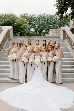 a group of women standing next to each other in front of some stairs with bouquets