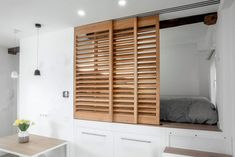 a bedroom with white walls and wooden shutters