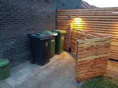 two trash cans are next to a wooden fence