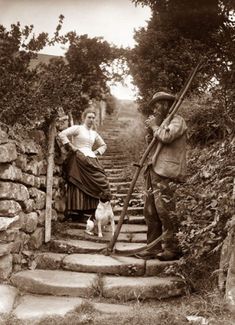 an old photo of a woman and a man on some stairs with a dog in the foreground