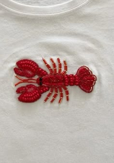 a red lobster embroidered onto a white t - shirt