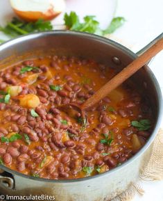 a pot filled with beans and garnish on top of a white tablecloth