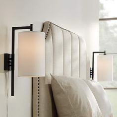 a lamp that is on the side of a wall next to a bed with pillows