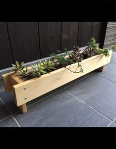 a wooden planter filled with succulents sitting on top of a patio