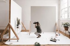 a woman kneeling down in front of a white wall taking a photo with her camera