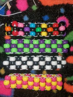 several different colored beads are arranged on a black tablecloth with multicolored dots