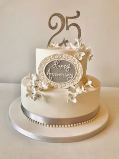 a white wedding cake with silver decorations and the number twenty five on it's side