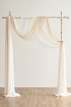 an arch made out of branches with white draping on the top and bottom