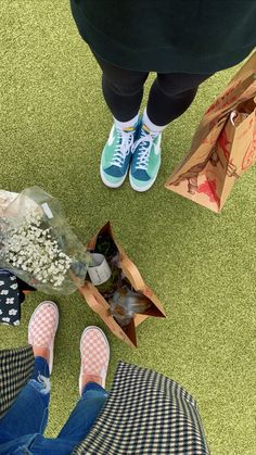 a person standing on the ground with flowers in their hand and two bags next to them