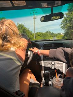 two people sitting in the driver's seat of a car and one person is driving