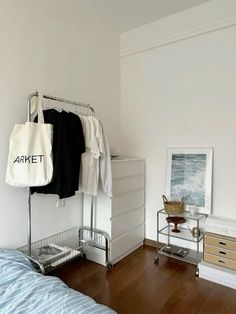 a bedroom with a bed, dresser and hanging clothes rack in the middle of it