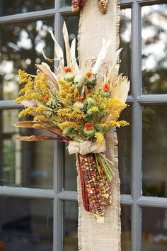 a bouquet of flowers hanging from the side of a window sill in front of a glass door