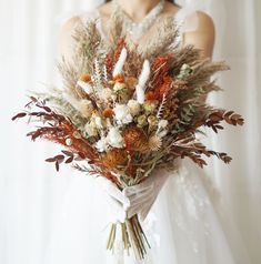 a bride holding a bouquet of dried flowers