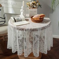 a table topped with a bowl of bread next to a candle and vase filled with flowers