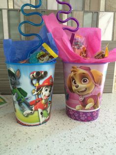 two plastic cups filled with toys on top of a counter