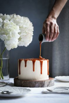 someone is decorating a cake with caramel icing