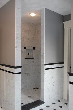 a bathroom with black and white tile on the floor, walls and shower stall area