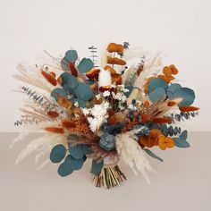 an arrangement of dried flowers and foliage on a table