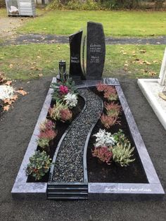 a grave sits in the middle of a gravel path with succulents and flowers