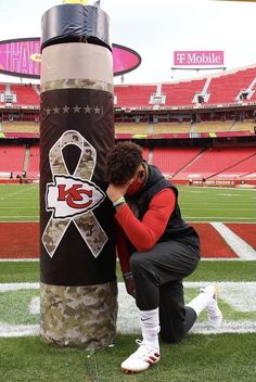 a man kneeling down next to a giant punching bag at a football stadium with an american flag on it