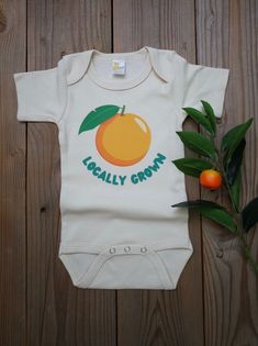 Do you have a 'locally grown' little one- or know someone who does? This bodysuit makes a great gift, baby announcement or just a cute everyday outfit! Image is a DTF transfer and will last through all the washes! Comfy enough for your little one to play in all day!  All shirts are made to order and my current turn around time is about 2 weeks until your order will ship. Please keep this in mind when ordering. Cute Short Sleeve Bodysuit For First Birthday, Spring Organic Cotton Fitted Bodysuit, Fitted Short Sleeve Organic Cotton Bodysuit For Summer, Fitted Organic Cotton Bodysuit With Short Sleeves, Fitted Organic Cotton Short Sleeve Bodysuit, Fitted Short Sleeve Bodysuit In Organic Cotton For Summer, Spring Cotton Bodysuit For First Birthday, Organic Cotton Short Sleeve Bodysuit For Spring, Cute Orange Cotton Onesie