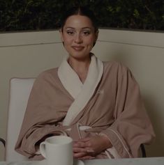 a woman wearing a robe and holding a coffee cup