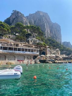 people are swimming in the water near a beach with boats and buildings on it's side