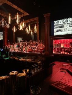 a dimly lit bar with lots of bottles on the shelves and lights hanging from the ceiling