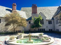 a fountain in the middle of a courtyard with two chimneys on top of each building