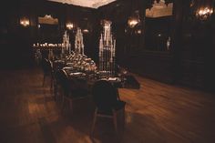 a dining room with wooden floors and chandeliers on the ceiling, lit by candles