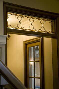 an open door with a stained glass window on the top and stairs leading up to it