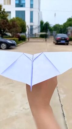 an open umbrella sitting on the side of a road in front of a building with cars