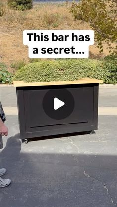 a man standing next to a black box with the words this bar has a secret on it