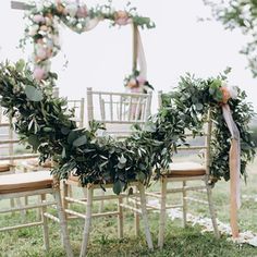 the chairs are decorated with greenery and ribbons for an outdoor wedding ceremony or reception