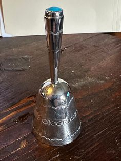 a metal bell sitting on top of a wooden table