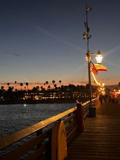 a pier at night with people walking on it and an american flag hanging from the pole