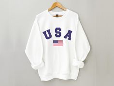 USA Sweatshirt, USA Crewneck, American Flag Shirt, 4th of July Sweatshirt, Patriotic Shirt, Red White & Blue, 4th of July Shirt for Women *Please note that we do not guarantee delivery before 4 of July - no matter the order date* * Super soft sweatshirt made of 50% cotton 50% polyester. * Design is high-quality screen printed. * Classic fit - Size up if you want a looser fit. * Unisex sizing - See pictures for size guide. Wash inside out using mild detergent. Let hang dry. If you have any qu Long Sleeve Cotton Tops For 4th Of July, Cotton Long Sleeve Top For 4th Of July, Patriotic American Flag Long Sleeve Tops, Long Sleeve Relaxed Fit T-shirt For 4th Of July, Patriotic White Cotton Sweatshirt, Independence Day Casual Letter Print Sweatshirt, Casual Letter Print Sweatshirt For Independence Day, Independence Day Letter Print Sweatshirt, Patriotic Crew Neck T-shirt For Fall