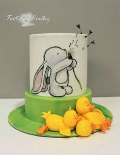 a cake decorated with an image of a bunny holding a flower in front of rubber ducks